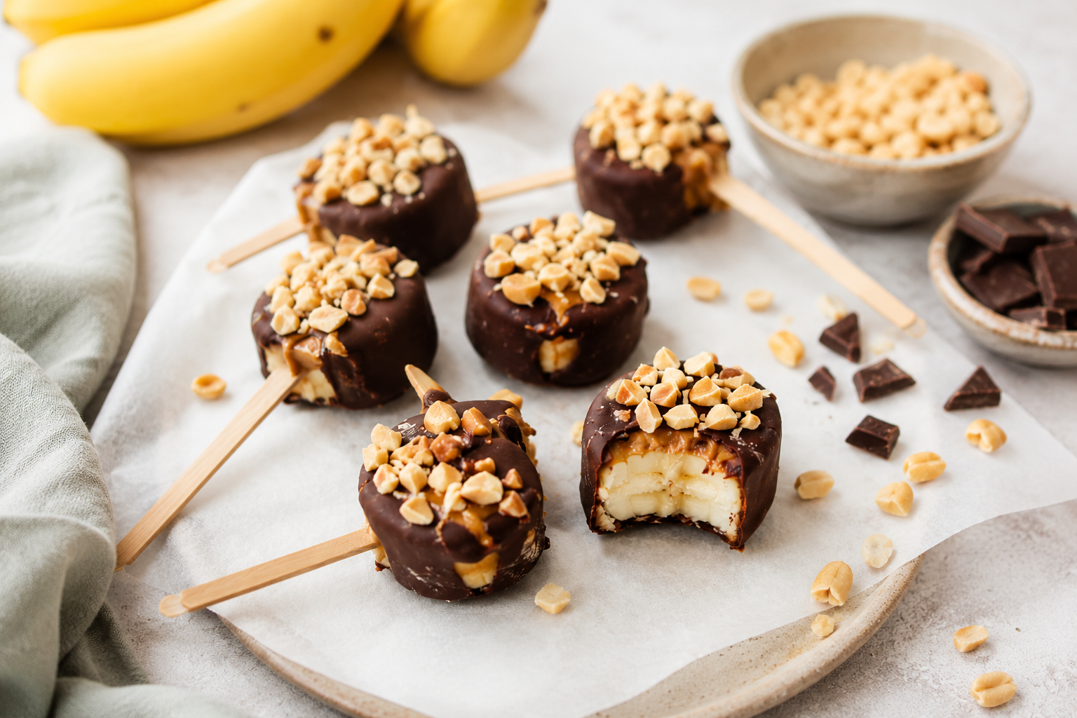 Auf diesem Bild sieht man ein gesundes Dessert, nämlich Bananen-Schokolade-Erdnussmus-Lollies