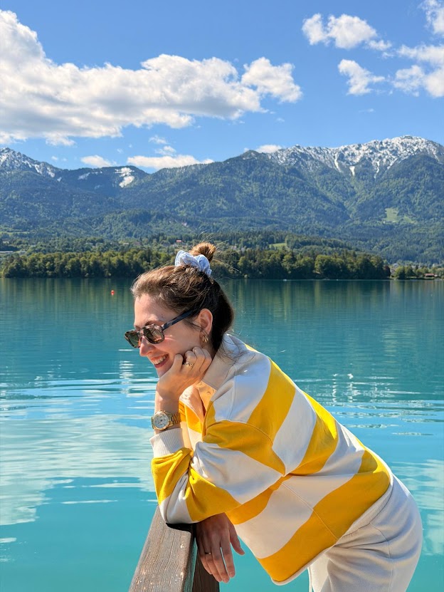 Diätologin Carina Palm steht glücklich an einem Steg. Dahinter sieht man die österreichischen Berge und den Faakersee.